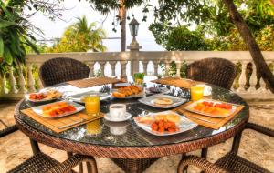 a table with plates of food and orange juice at Santorini Villas del Mar Santa Marta in Santa Marta