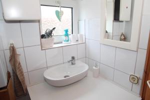 uma casa de banho branca com um lavatório e uma janela em Sandkasten em Upleward