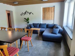 sala de estar con sofá azul, mesa y sillas en Zum Hüttenklaus - 12 Personen Gruppenunterkunft in den Bergen mit eigenem Badezuber en Bad Hindelang
