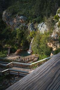 a bridge over a river with a waterfall in the background at Casa das Ruas (Xisto Sentido®) 