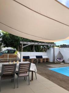 eine Terrasse mit einem Tisch, Stühlen und einem weißen Regenschirm in der Unterkunft Amalfi Villa in Grand Baie