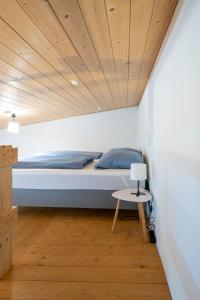 Ce lit se trouve dans un dortoir doté d'un plafond en bois. dans l'établissement feworld living - near Salzburg city, à Freilassing
