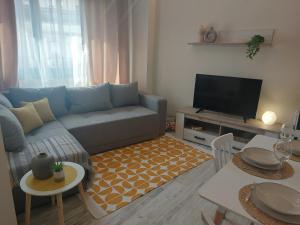 een woonkamer met een blauwe bank en een televisie bij Villanova - Emerald Suite in Thessaloniki