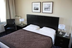 a bedroom with a large bed and a chair at Hotel Aguado in Dieppe