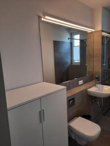 ein Badezimmer mit einem WC, einem Waschbecken und einem Spiegel in der Unterkunft Haus Am Anger in Hangelsberg