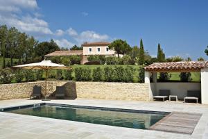una piscina con sombrilla y una casa en Coquillade Provence en Gargas
