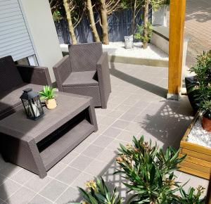 a patio with two chairs and a table and some plants at Chez SOPHIE, logement avec jacuzzi et salle cinéma in Altviller