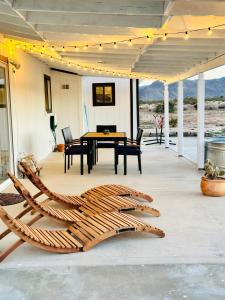 a wooden chair sitting on a patio with a table at Ravens Nest Ranch, Fire pit , Views, Near JT Park! in Joshua Tree