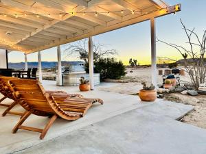 een houten schommelstoel onder een paviljoen op het strand bij Ravens Nest Ranch, Fire pit , Views, Near JT Park! in Joshua Tree