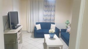 a living room with a blue couch and a tv at Evelyn Home in Limenas