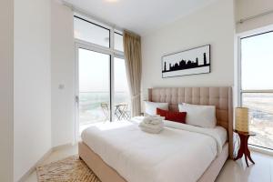 a white bedroom with a large bed and large windows at Key View - Carson A, DAMAC Hills in Dubai Marina