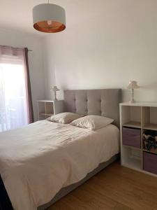 1 dormitorio con 1 cama grande con sábanas blancas y ventana en Jolie T2 en rez-de-jardin a 150m du lac, en Aix-les-Bains