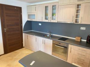 cocina con armarios de madera, fregadero y puerta en Port Balchik apartment, en Balchik