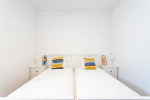 two beds in a room with white walls at Villa Jacarandá in Cascais