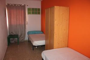 ein kleines Zimmer mit 2 Betten und einer orangefarbenen Wand in der Unterkunft Wimpy Solo Familias Serviplaya in Casas Las Basas