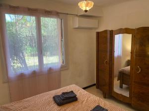 1 dormitorio con espejo, cama y ventana en Appartement F3 de 60 m² au rez de chaussée d'une villa, en Vézénobres