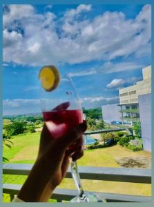 a hand holding a wine glass with a lemon on it at Amaia Steps Altaraza by GEMcondotel in Tunkong Manga