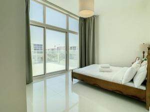 a bedroom with a bed and a large window at Key View - Pacifica, Damac Hills 2 in ‘Ūd al Bayḑāʼ
