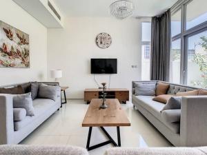 a living room with two couches and a tv at Key View - Pacifica, Damac Hills 2 in ‘Ūd al Bayḑāʼ