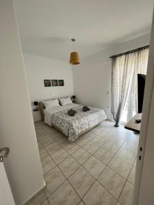 a bedroom with a bed and a tiled floor at Porfyra Apartment Portoheli in Porto Heli
