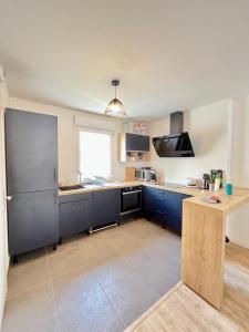a large kitchen with blue cabinets and a large window at Amsterdam - Bel appartement in Bezannes-les-Reims