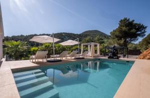 una piscina con tumbonas y sombrillas en Villa Romeo en Ibiza