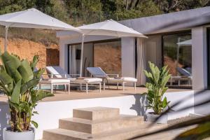 Villa Romeo في مدينة إيبيزا: فناء به كراسي ومظلات على المنزل