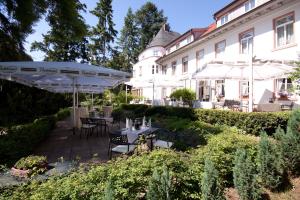 Hofgut Dippelshof Hotel- und Restaurant KG في دارمشتات: حديقة فيها طاولات ومظلات امام المبنى