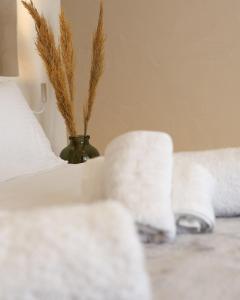 een bed met witte lakens en een vaas van tarwe bij Thermes private suites in Loutraki