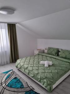 a bedroom with a green bed with two towels on it at Izabella Guest House in Săcele