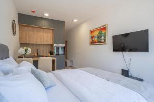 a bedroom with two white beds and a kitchen at Andjela's Studio in Kotor