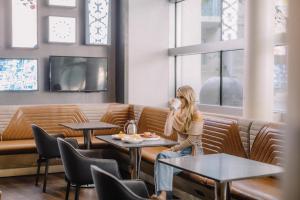 a woman sitting on a bench in a restaurant talking on a cell phone at San Jose Marriott in San Jose