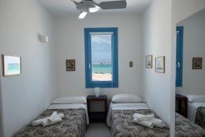 two beds in a room with a window at Casa Blu sul mare e centralissima in San Vito lo Capo