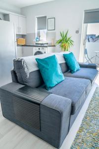 a gray couch with blue pillows in a living room at Causeway Coast Beach Front Apartment - Ballycastle in Ballycastle