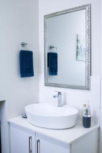 a white bathroom with a sink and a mirror at Cottage with a View in St Francis Bay