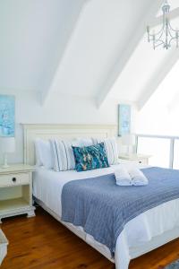 a bedroom with a white bed with blue blankets and pillows at Cottage with a View in St Francis Bay