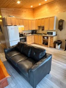 um sofá de couro numa cozinha com armários de madeira em Sun Rise delight! em Bella Bella
