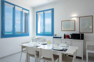 un comedor blanco con una mesa y sillas blancas en Casa Blu sul mare e centralissima, en San Vito lo Capo