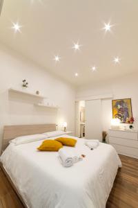 a white bedroom with a large white bed with yellow pillows at Appartamento nel cuore di Messina in Messina