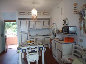 eine kleine Küche mit einem Tisch und einer Mikrowelle in der Unterkunft Villetta Susy in Costa Paradiso