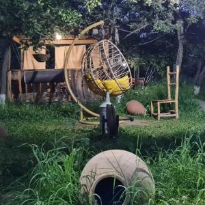 a garden with an old fashioned wheel and a swing at Mirage guesthouse in Khot