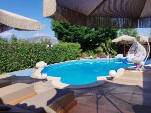 a swimming pool with chairs and an umbrella at Luxury Villas Chrysa Private Pool & Spa in Nafplio