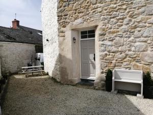 a stone house with a white door and a stone wall at Old Chapel in St Just