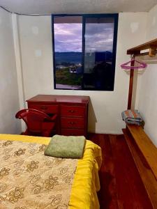 1 dormitorio con cama, escritorio y ventana en Casa nómada Puyo, en Puyo