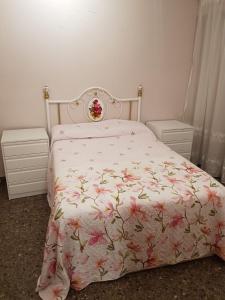 1 dormitorio con 1 cama con colcha rosada de flores en Apartamento Sol y Playa, en Puerto Sagunto