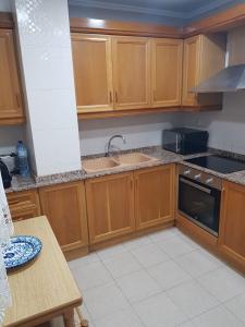 Una cocina con gabinetes de madera y un fregadero. en Apartamento Sol y Playa, en Puerto Sagunto