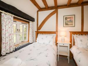 two beds in a room with a window at Wren Cottage in Canterbury