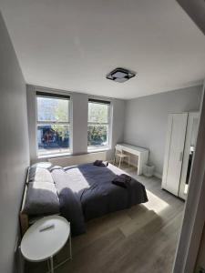 a bedroom with a bed and a table and two windows at Beautiful 2-Bed Apartment in London - Sleeps 6! in London