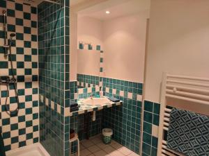 baño con lavabo y azulejos verdes en La ferme des douceurs, en Cervon