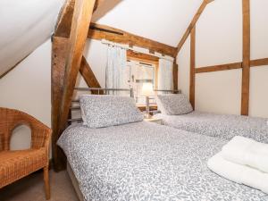 a bedroom with two beds and a chair at Blackbird Cottage in Canterbury
